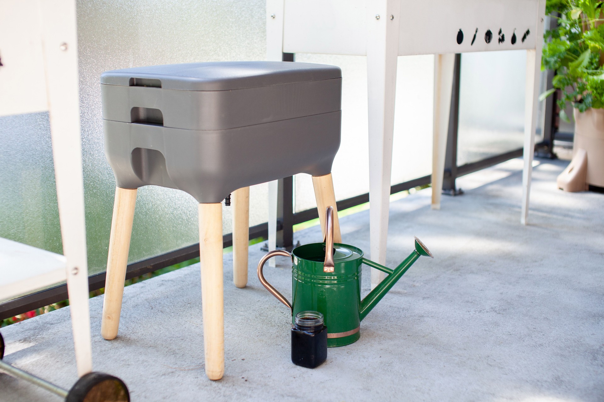 A vermicomposting system (worm composter) sits on an apartment balcony